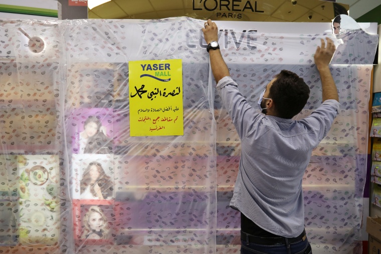 A worker of a mall covers French products in protest against French cartoons of the Prophet Mohammad in Amman
